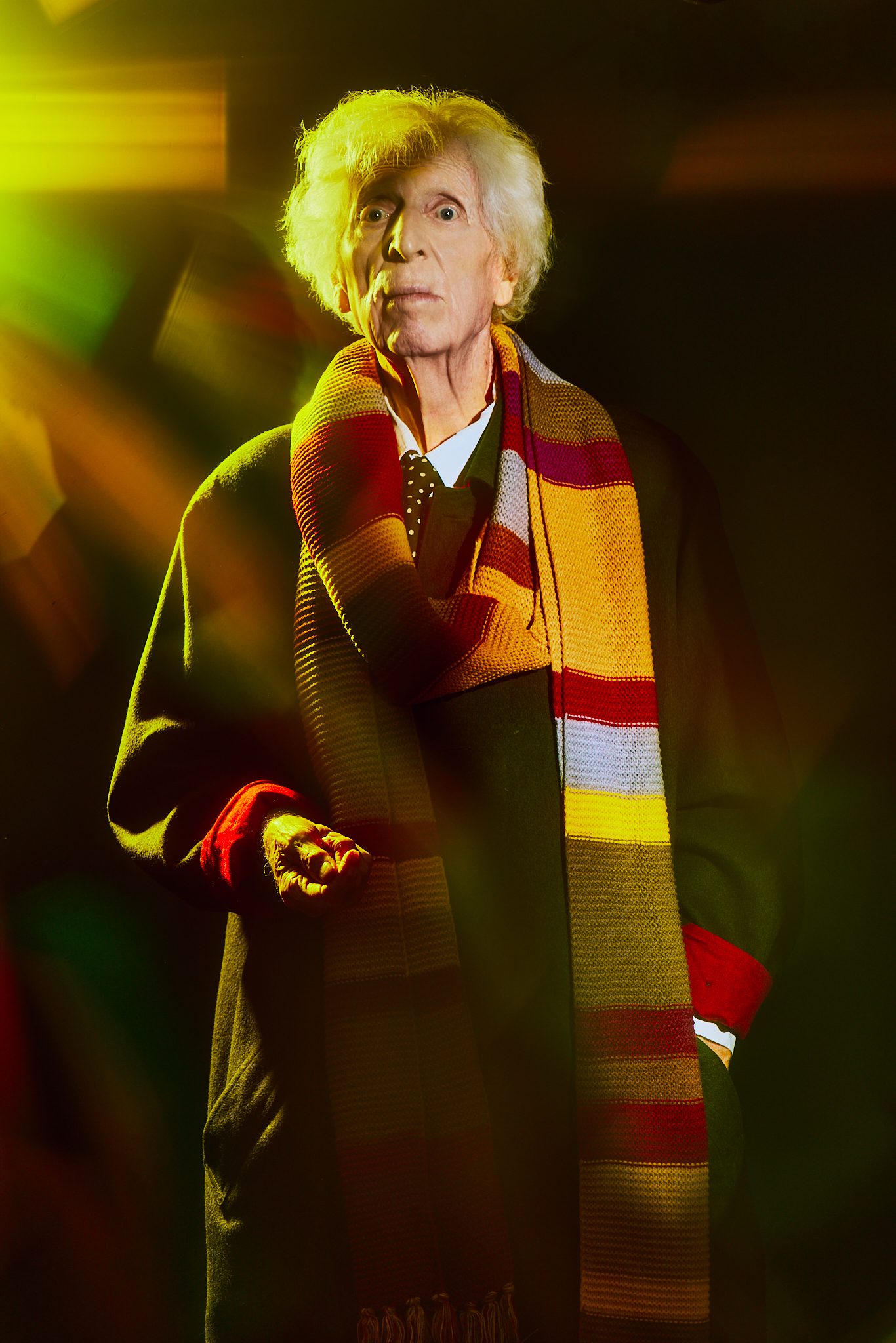 Tom Baker in a replica of his Fourth Doctor scarf, standing up.